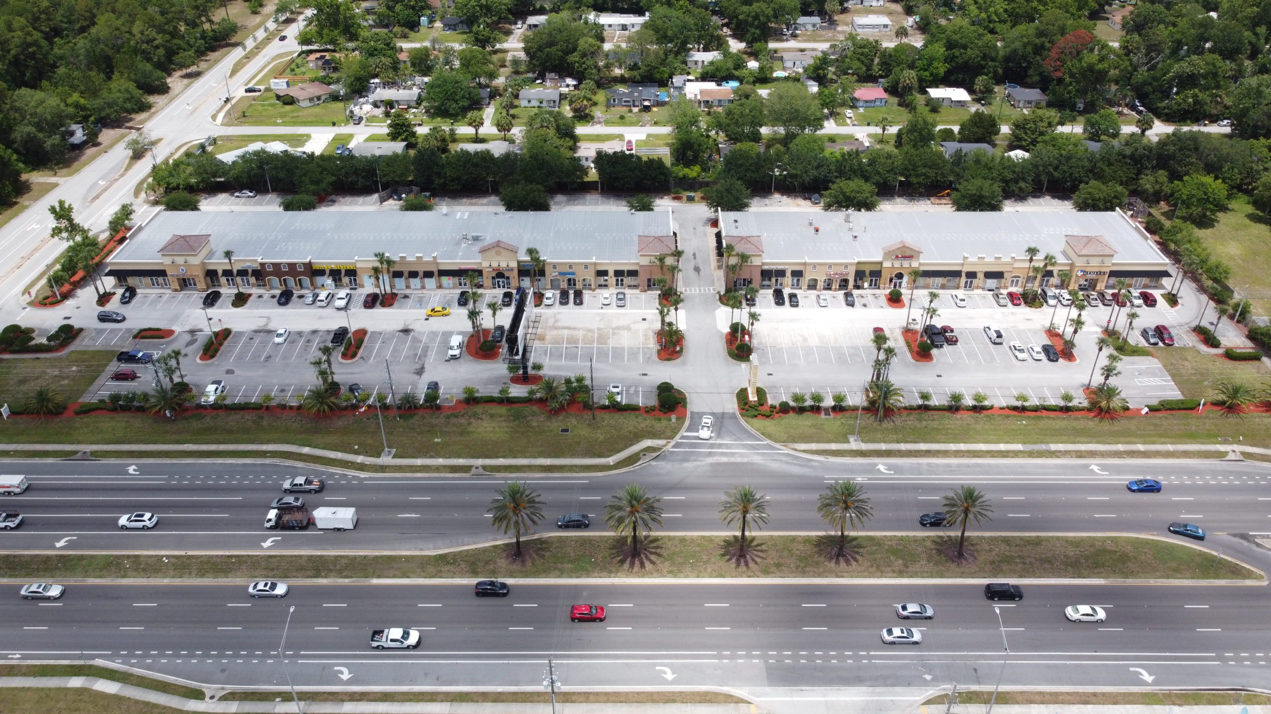 An aerial view of a one-story retail center and car park.