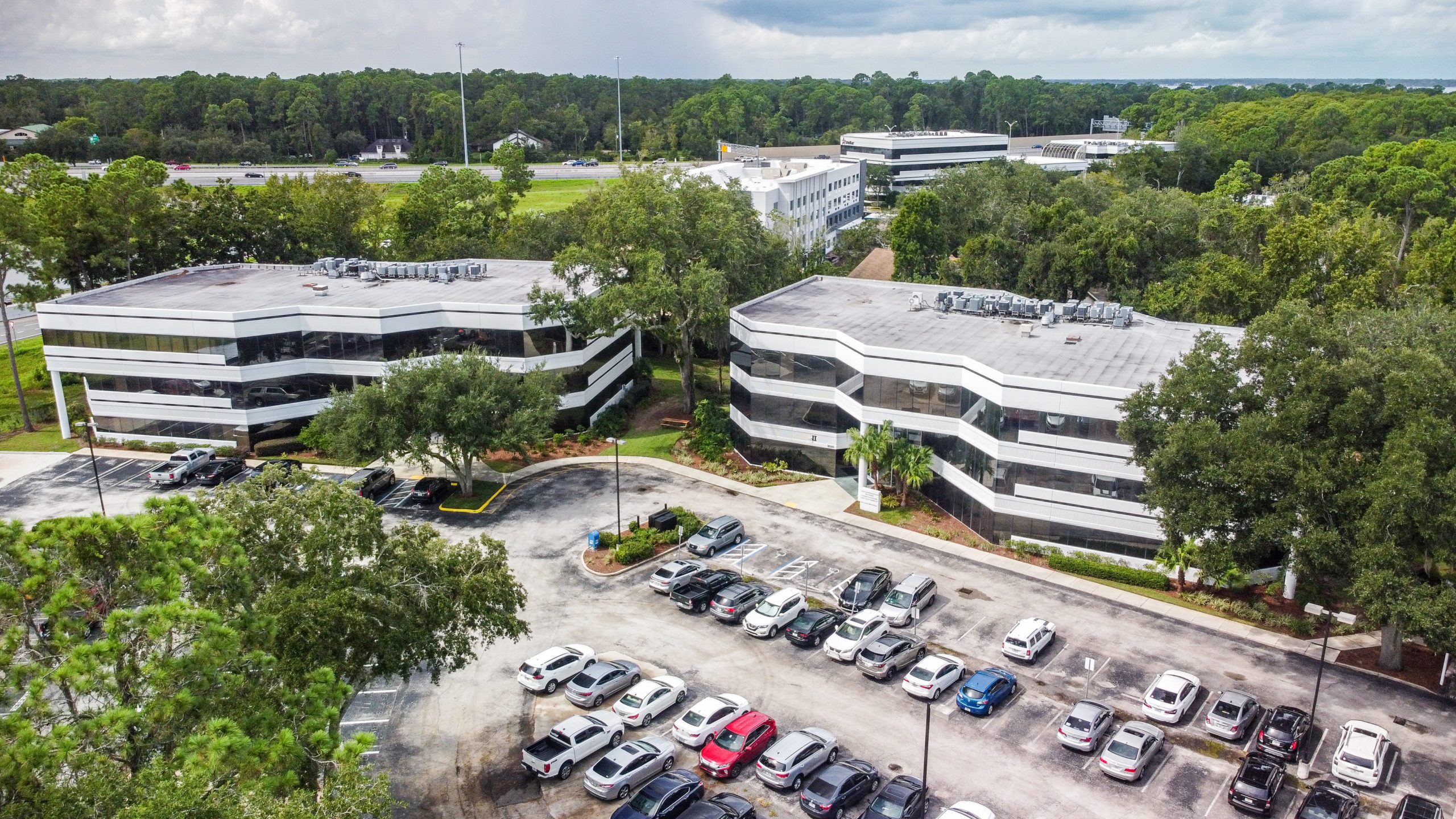 An aerial view of a three-story office building and car park.